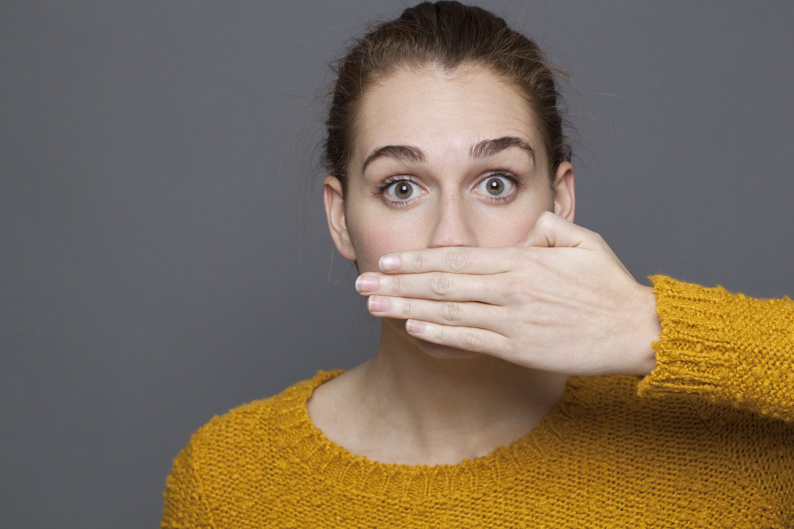 woman covering her mouth and shielding her bad breath